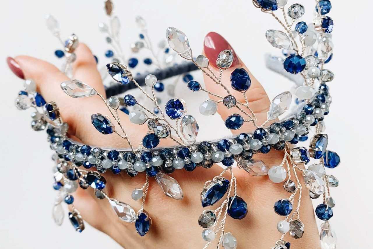 Ruka koja drži ogrlicu sa safirima i dijamantima.